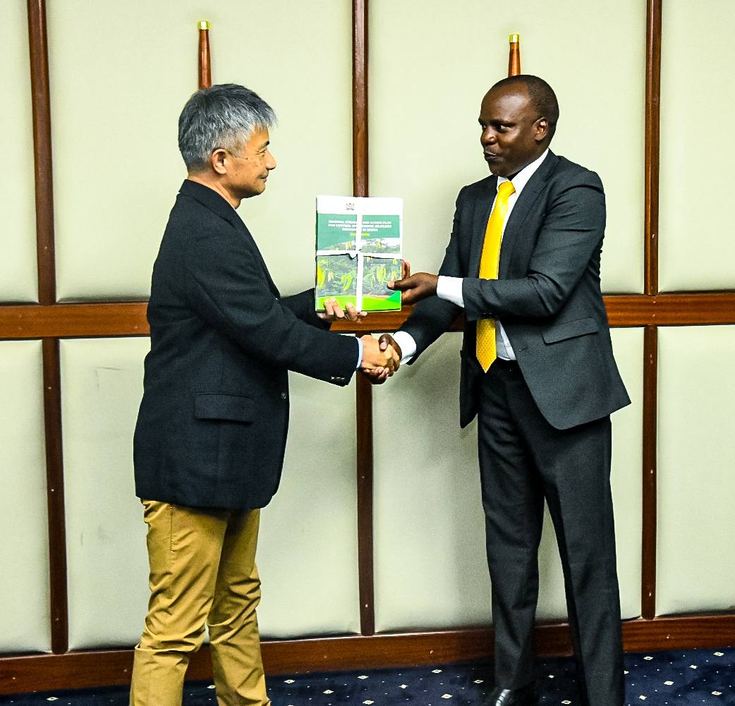Forest Development Secretary Mr. George Tarus presents key policy documents to Dr. Hiroshi Imae of the Japan International Cooperation Agency (JICA).