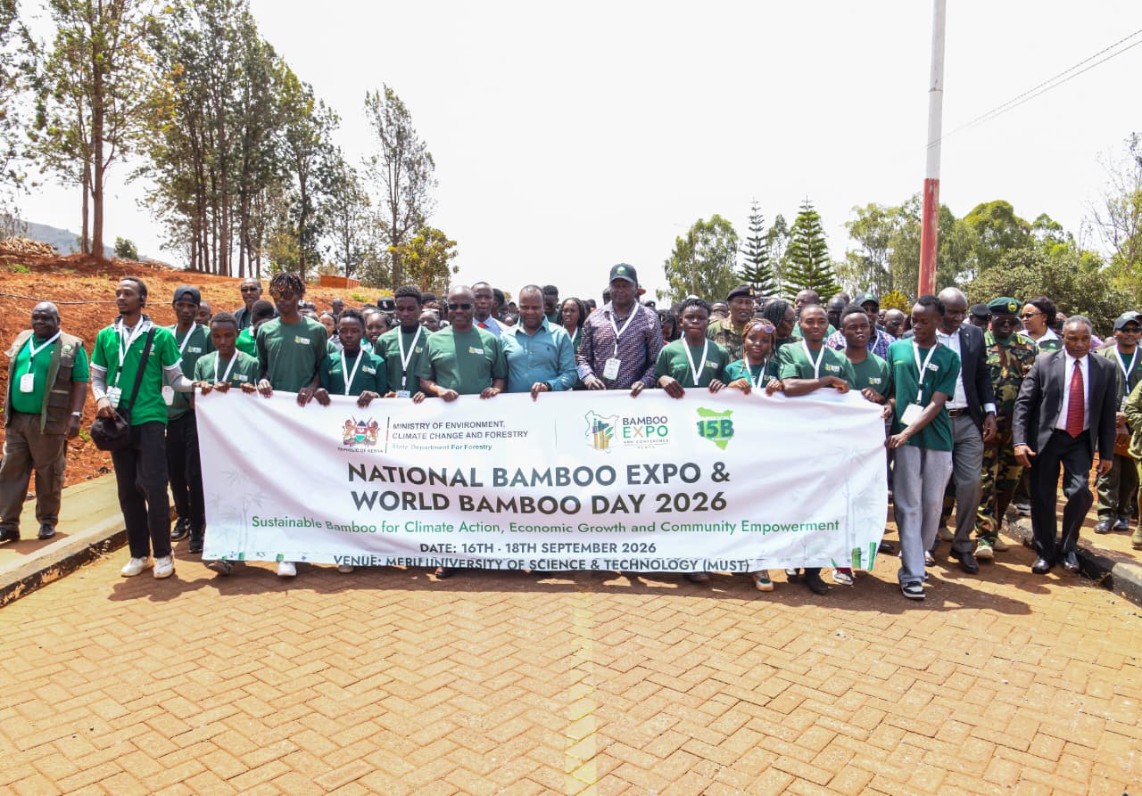 Forest Development Secretary Mr. George Tarus walks alongside Meru University students while holding a World Bamboo Day Banner
