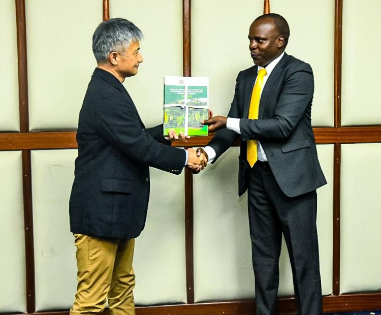 Forest Development Secretary Mr. George Tarus presents key policy documents to Dr. Hiroshi Imae of the Japan International Cooperation Agency (JICA).